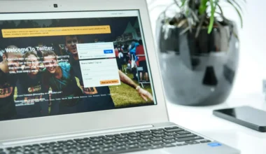 A laptop showing the Twitter login page with a user interface for account access.