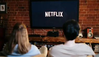 Two individuals watching Netflix on a television screen in a living room setting.